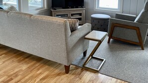 A living room with a sofa, armchair, TV, and wooden beams. - NUBBLE LIGHT VIEWS (York)