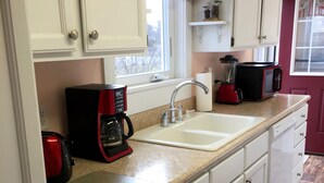 A kitchen with white cabinets, a double sink, a red coffee maker, and a microwave. - NUBBLE LIGHT VIEWS (York)