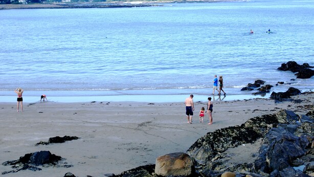 A beach with people walking and playing, rocky shoreline, and calm water. - NUBBLE LIGHT VIEWS (York)