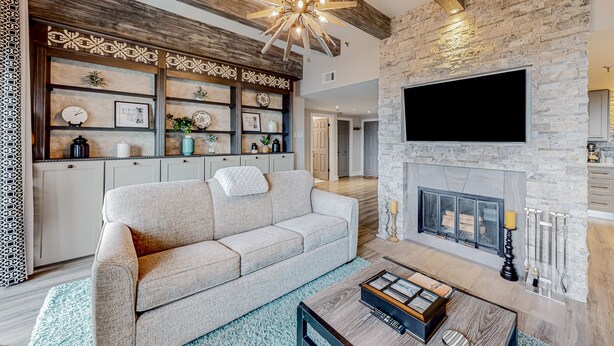 A modern living room with a stone fireplace, a sofa, and a coffee table. - Wilderness retreat with pool, hot tub, and sauna access - wood-burning fireplace (Sugar Mountain)