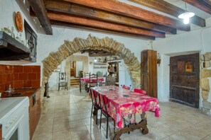 Un coin repas rustique agrémenté d’une arche en pierre, de poutres en bois et d’un sol carrelé.