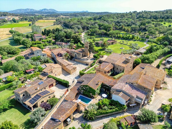 Un village traditionnel avec des bâtiments en pierre, une piscine et une végétation luxuriante tout autour.