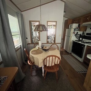 A compact kitchen with a dining table, chairs, and basic appliances.