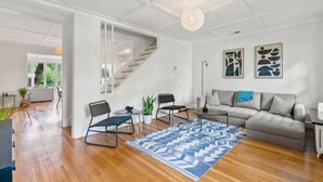 Ein modernes Wohnzimmer mit Treppe, Sofa, Couchtisch und einem gemusterten Teppich.