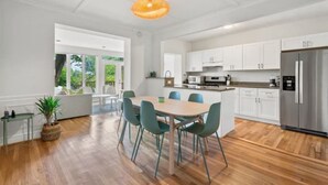Eine moderne Küche mit weißen Schränken, einem Edelstahl-Kühlschrank und einem Essbereich mit einem Holztisch und Stühlen.