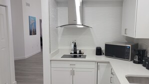 A modern kitchen with white cabinetry, a stainless steel range hood, a microwave, a toaster, and a coffee maker. - Cozy Private Stay. Near AMI Beaches & IMG Academy. Boats and jetskies driveway.  (Bradenton)