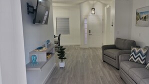 A living room with a grey sofa, a small table, and a potted plant. - Cozy Private Stay. Near AMI Beaches & IMG Academy. Boats and jetskies driveway.  (Bradenton)
