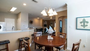 A dining area with a round wooden table, four chairs, and a chandelier.