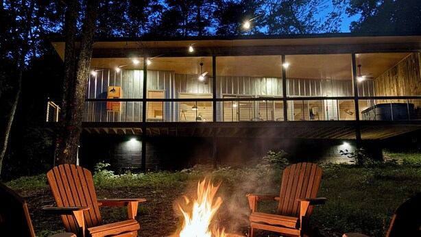 A modern building with a glass facade, a fire pit with chairs, and a tree in the foreground. - Scandinavian HideOut for Couples and Families, Firepit, Outdoor Games (Sevierville)