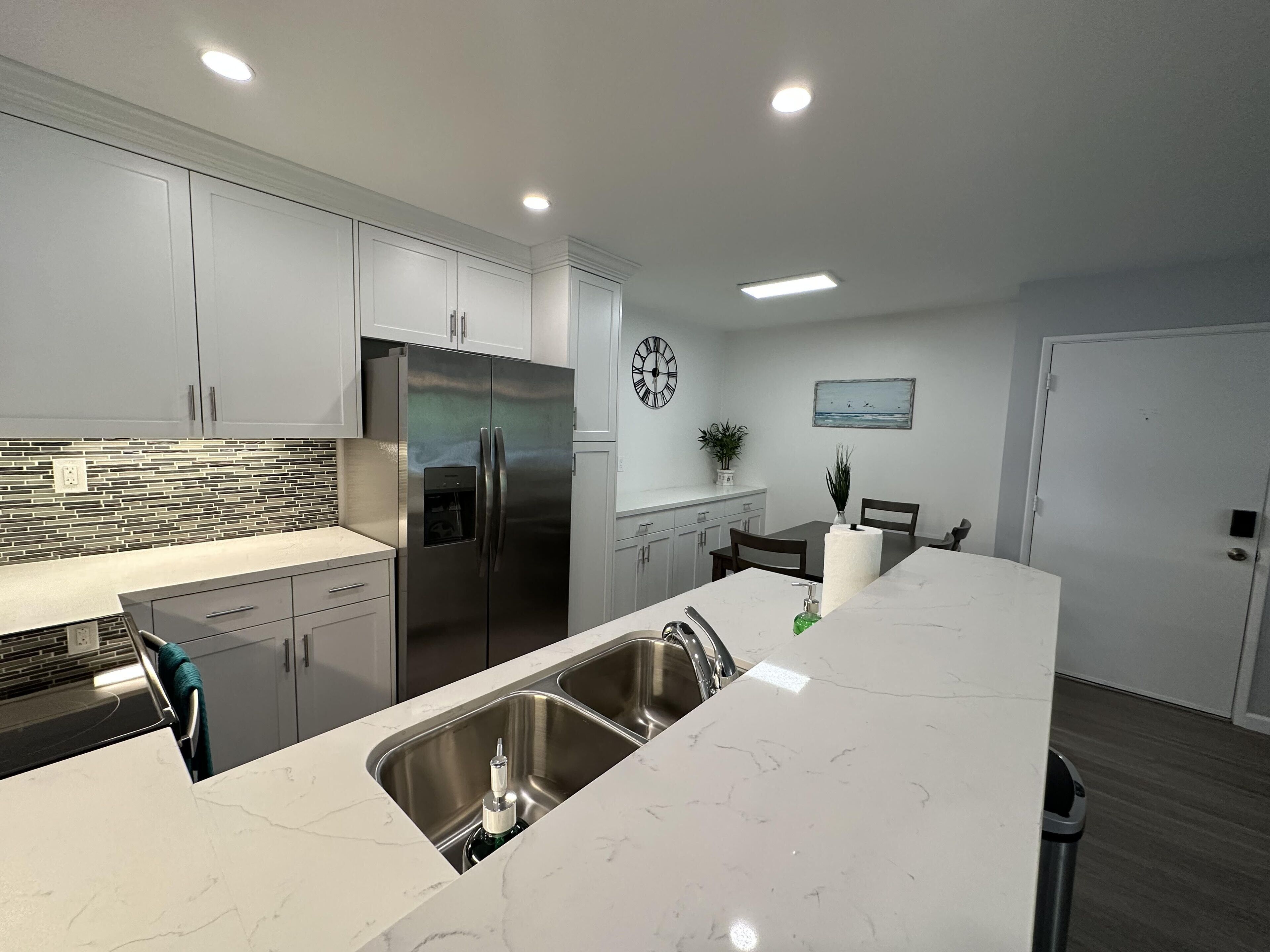 A modern kitchen with stainless steel appliances, a marble countertop, and a built-in sink.