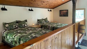 Ein Schlafzimmer mit zwei Betten, Holzbalkendecke und Blick ins Freie.