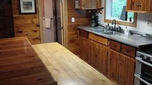 Eine Holz-Küche mit großem Tisch, Holzschränken, einem Fenster und einem eingebauten Backofen.