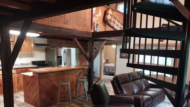 Ein geräumiges Wohnzimmer mit Holzboden, einem Ledersofa, einem Essbereich mit Holztisch und einer Küche mit modernen Geräten.