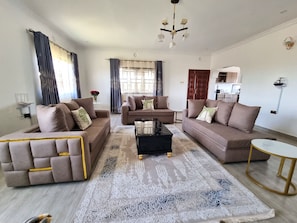 A modern living room with three sofas, a coffee table, and a rug. - Casa Nadreya (Nakuru)