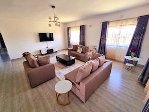 A modern living room with a sofa set, a coffee table, a TV, and a small side table. - Casa Nadreya (Nakuru)