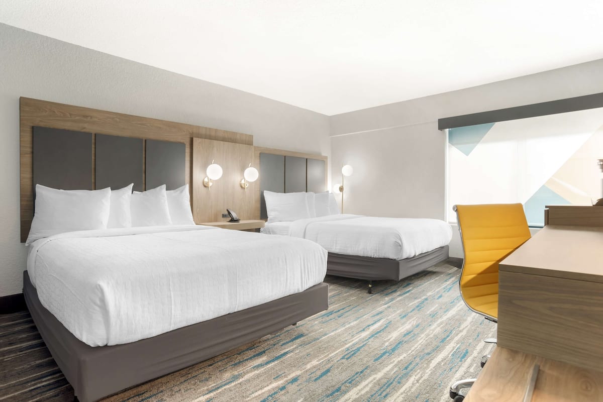 Una habitación de hotel con dos camas, un escritorio y una silla.