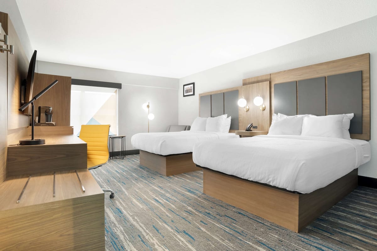 Habitación de hotel con dos camas, un escritorio y una silla.