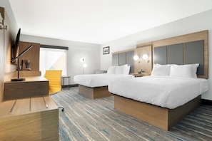 Quarto de hotel com duas camas, uma escrivaninha e uma cadeira.