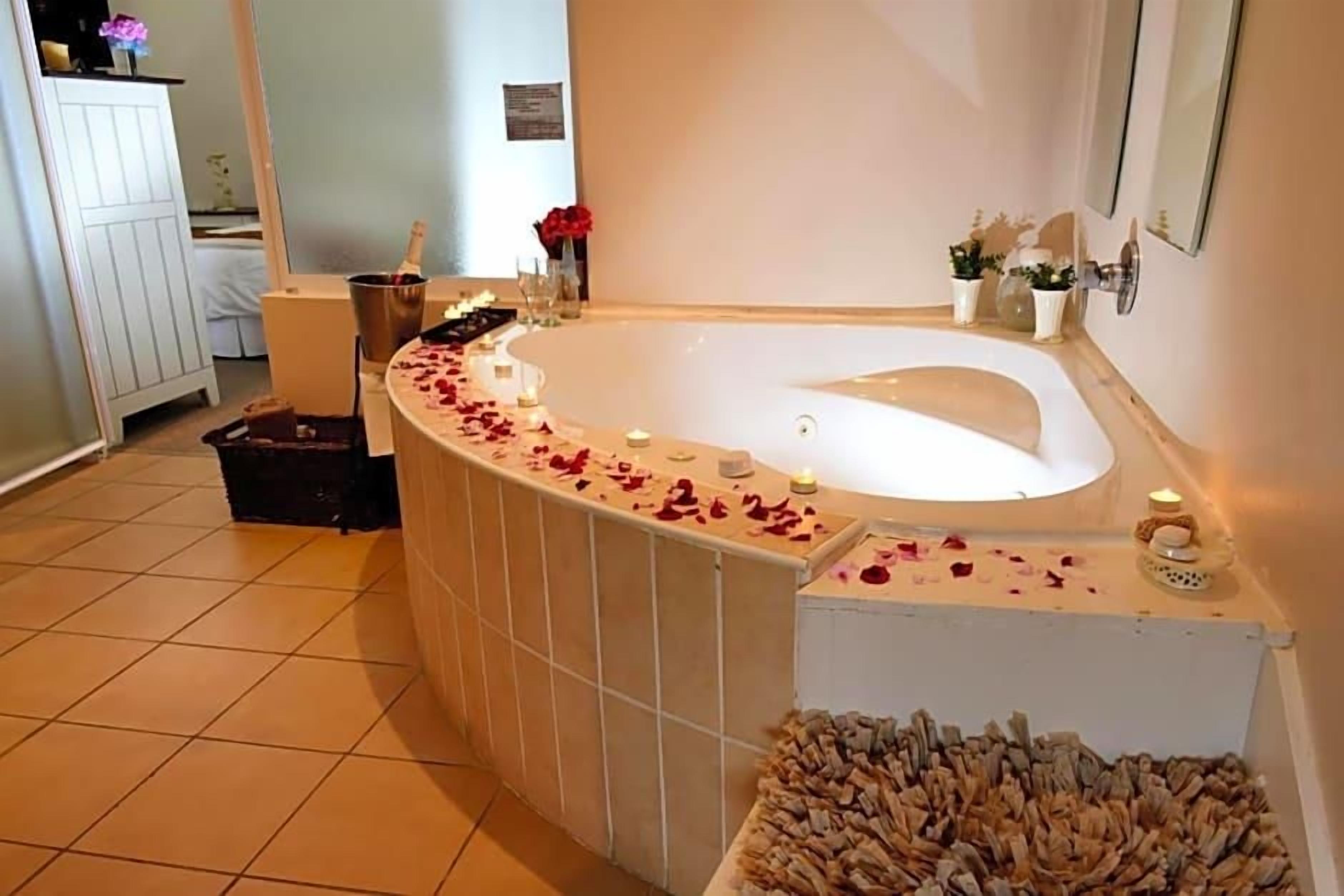 A bathroom with a large bathtub, a shower area, and a tiled floor.