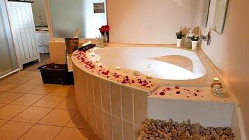 Un baño con una bañera grande, una zona de ducha y suelo de baldosas.