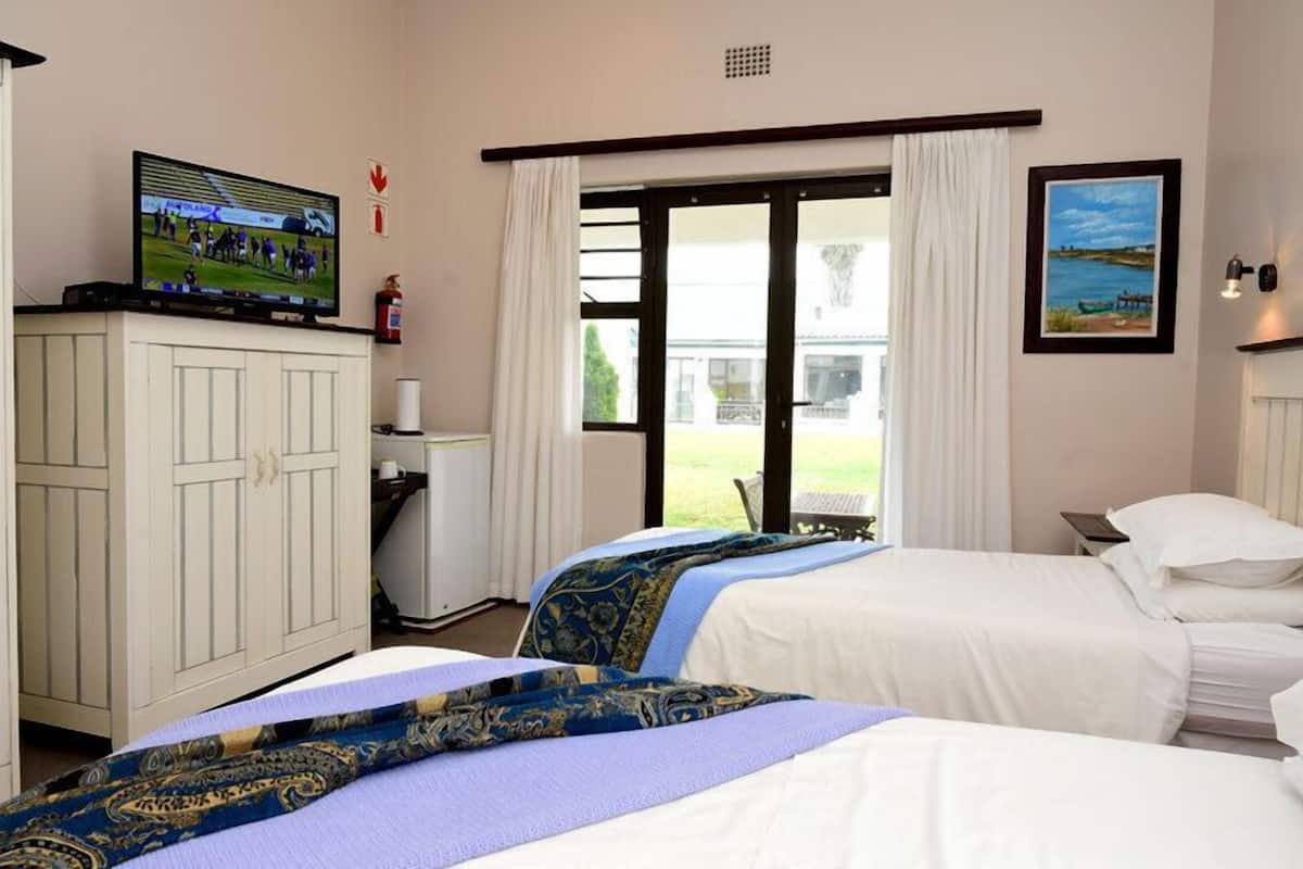 Une chambre d’hôtel avec deux lits, une télévision, un bureau et une fenêtre avec des rideaux.