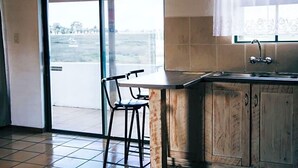 A kitchen with a large window, a sink, and a bar stool. - Riviera Hotel (Bergrivier)