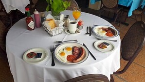 A round dining table with breakfast plates, condiments, and a beverage. - Riviera Hotel (Bergrivier)
