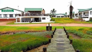 A wooden pathway leading to a hotel with a green roof and a sign that reads 'RIVIERA HOTEL Die Pont Restaurant.' - Riviera Hotel (Bergrivier)