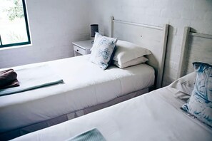 A room with a bed, a nightstand, and a window.