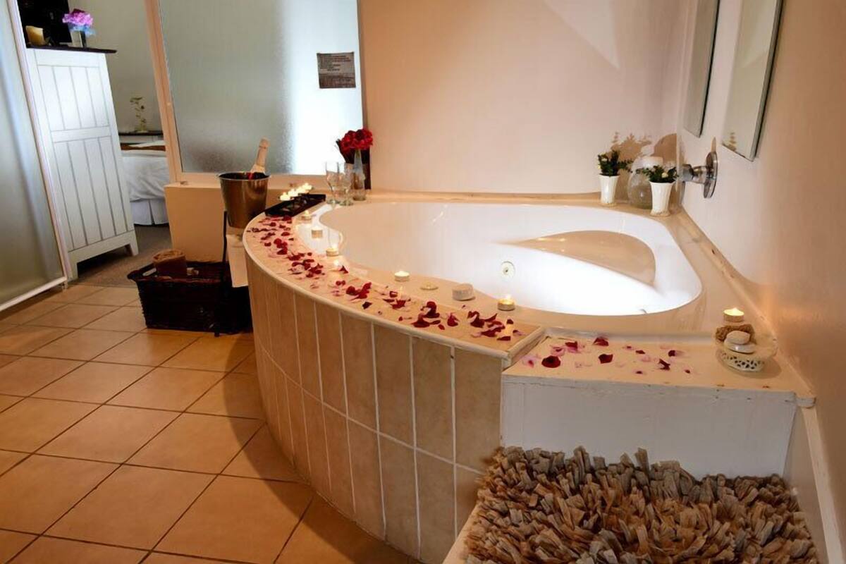 Une salle de bain avec une baignoire sur pieds, un banc en bois et un tas de copeaux de bois.