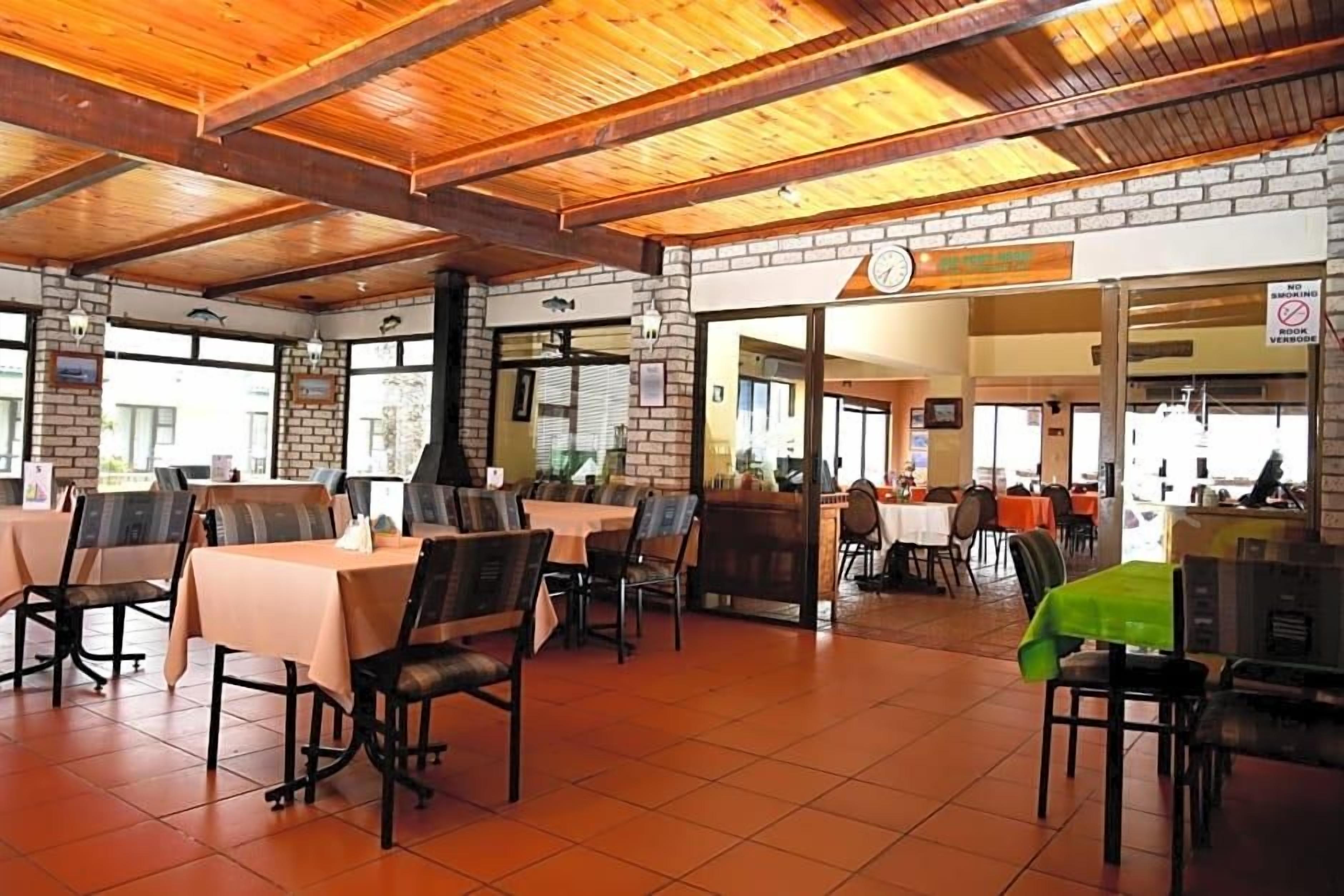 A restaurant with brick walls, wooden ceiling beams, and tables with chairs.