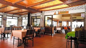 Un restaurante con paredes de ladrillo, vigas de madera en el techo y mesas con sillas.