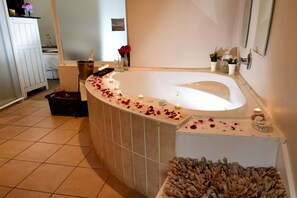 Un baño con una bañera independiente, un banco de madera y un montón de virutas de madera.