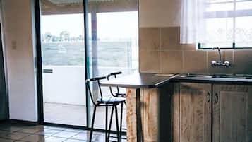 A kitchen with a large window, a sink, and a bar stool.