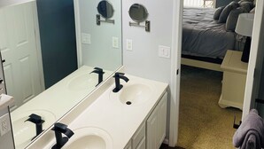 Une salle de bain moderne avec deux vasques, un grand miroir et un luminaire encastré au plafond.