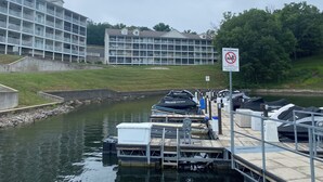 Un port de plaisance avec des bateaux amarrés, un panneau indiquant qu'il est interdit de se baigner, et un immeuble à plusieurs étages en arrière-plan.