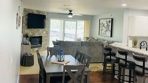 Une cuisine moderne avec un coin repas, un mur décoratif en pierre, un téléviseur à écran plat et un bar.
