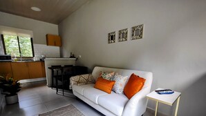 A modern living room with a white sofa, a small table, and a kitchen in the background.