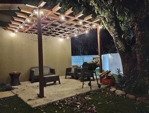 Un espace extérieur aménagé en terrasse, avec une pergola, des sièges et un barbecue.