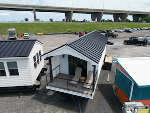 A small, single-story structure with a sloped roof, a balcony, and a covered outdoor area.