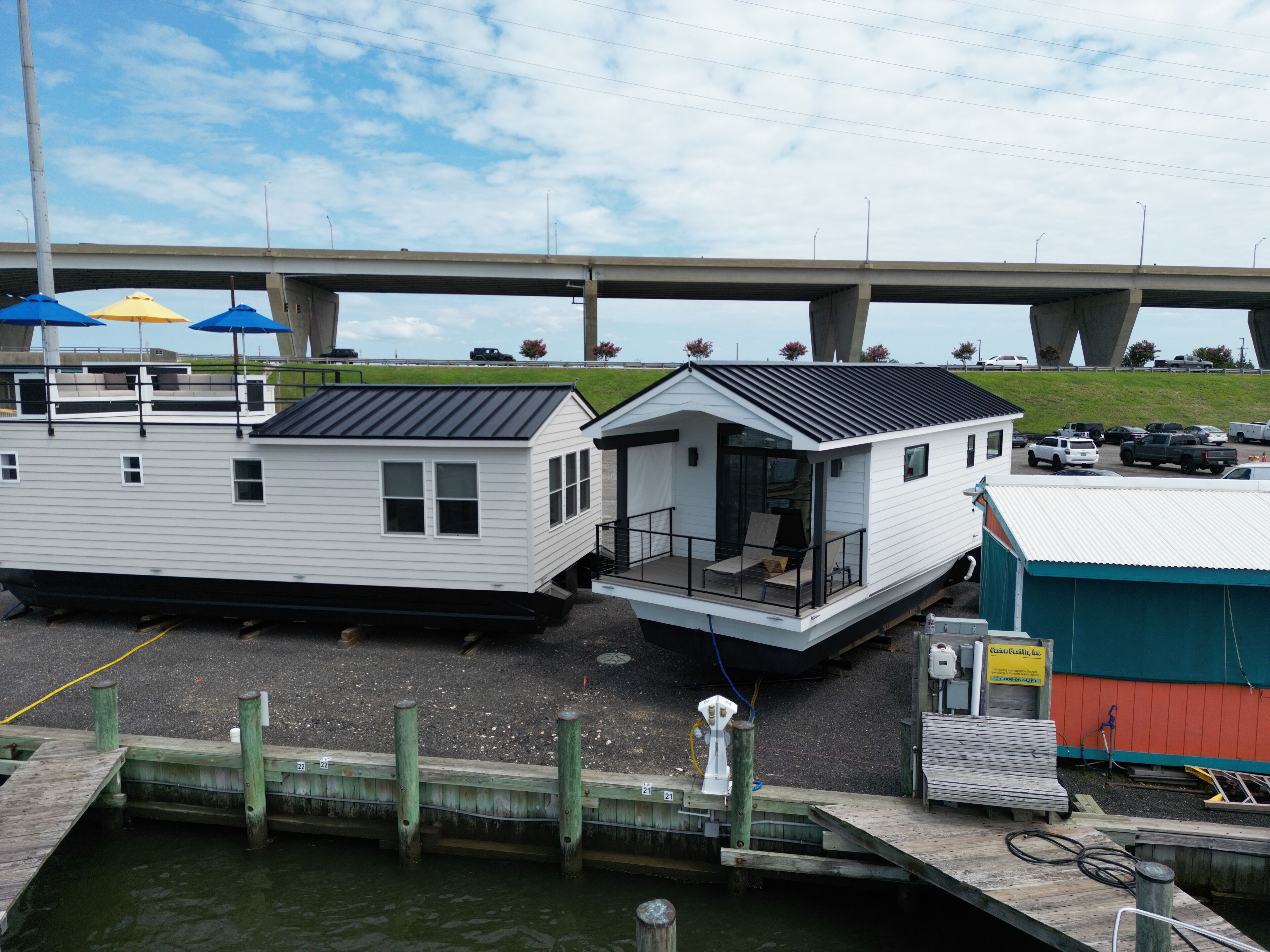 A waterfront property with a dock, a covered outdoor seating area, and a building with a balcony.
