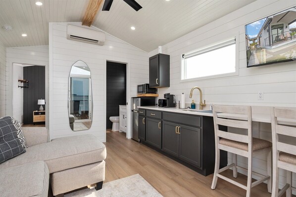 A modern kitchen with dark cabinets, a white countertop, and a large window.