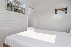 A bedroom with a bed, a wooden shelf, and a window with a view of a house and dock.