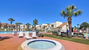A pool area with lounge chairs, a hot tub, and palm trees. - Walk to Beach! PCB Resort Condo w/ Pool Access (Panama City Beach)