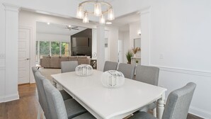 Un coin repas avec une table blanche, des chaises grises et un lustre.