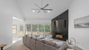 Un salon moderne avec un canapé d’angle, une cheminée et un ventilateur de plafond.