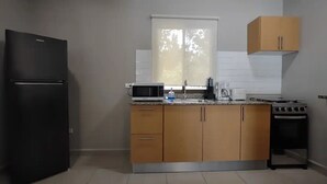 A kitchen with a black refrigerator, a microwave, a coffee maker, and a stove.