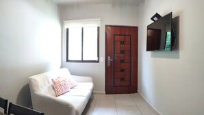A hallway with a white sofa, a wooden door, and a TV mounted on the wall.