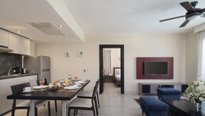 A modern living space with a dining area, kitchen, and a TV mounted on the wall. - THE ROYAL SUITES - WALKING DISTANCE TO 8 BEACHES - ALL INCLUSIVE (Cofresi)