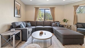 A modern living room with a sectional sofa, a round coffee table, and a small side table. - ✨ 3-King Beds / HotTub / EV Charger / Mountain View / Walk to River & Dining (Three Rivers)